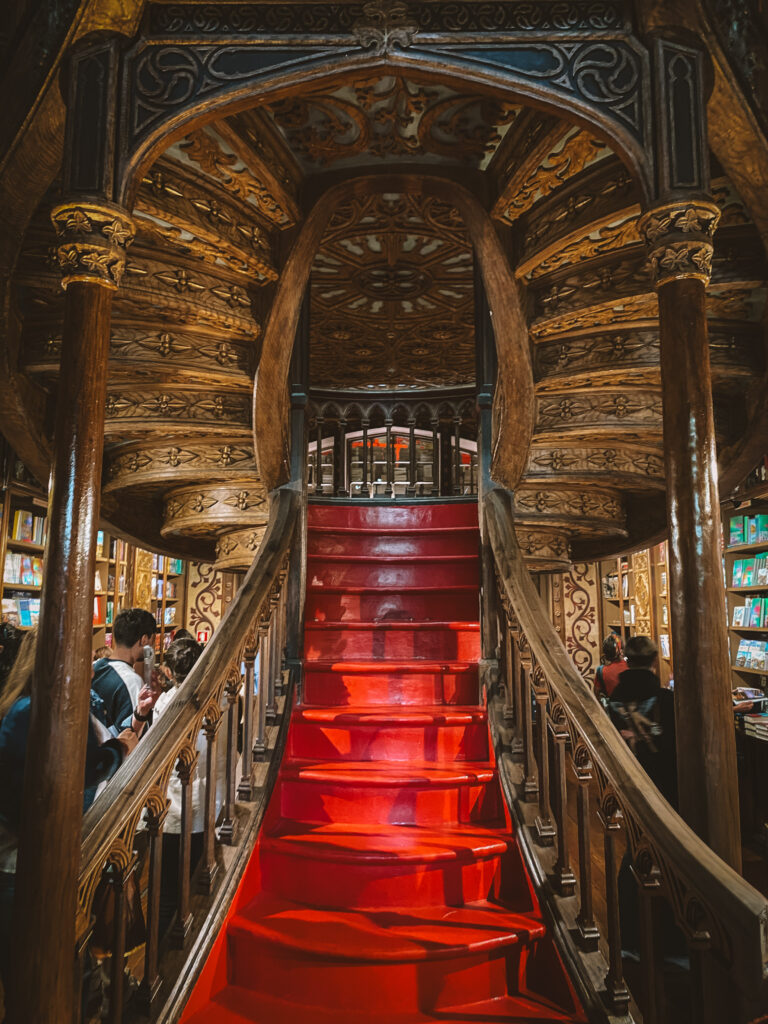 Grand red wooden staircase with intricate carvings in a neo-Gothic interior