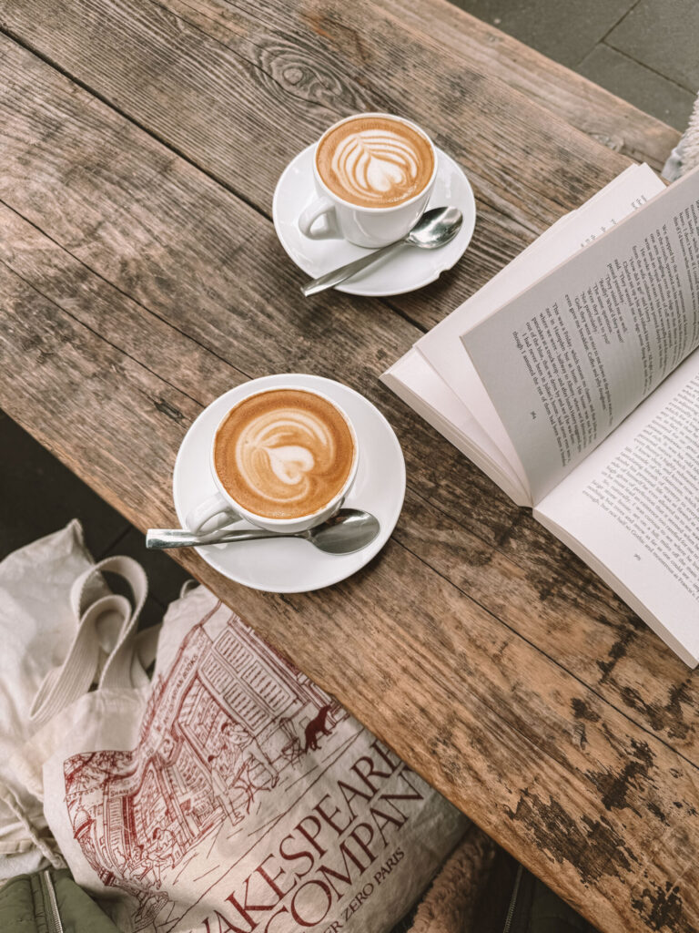 speciality coffee and a book on a wooden coffee table outside