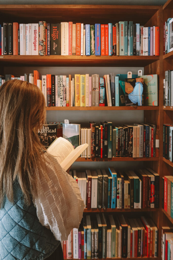 Lesende Person vor einem Bücherregal
